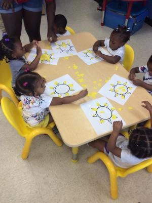 Children coloring sun drawings at a table