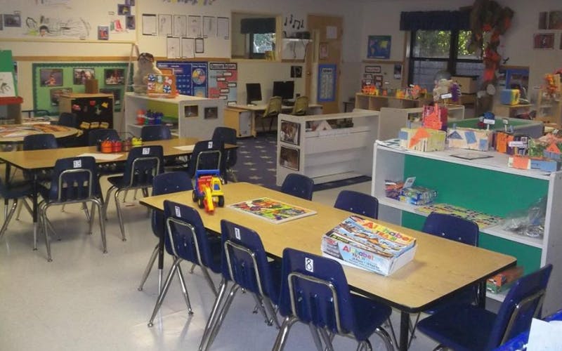 Classroom with child-sized tables and chairs, educational materials, and art displays