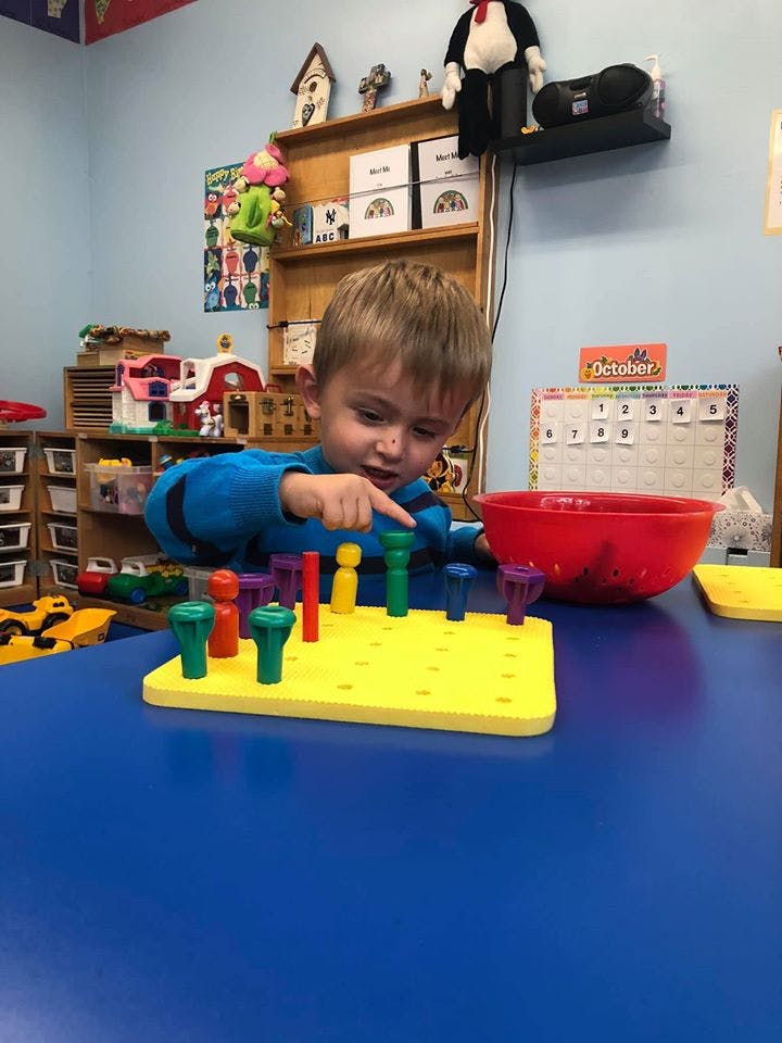 Child playing with a pegboard toy in a classroom
