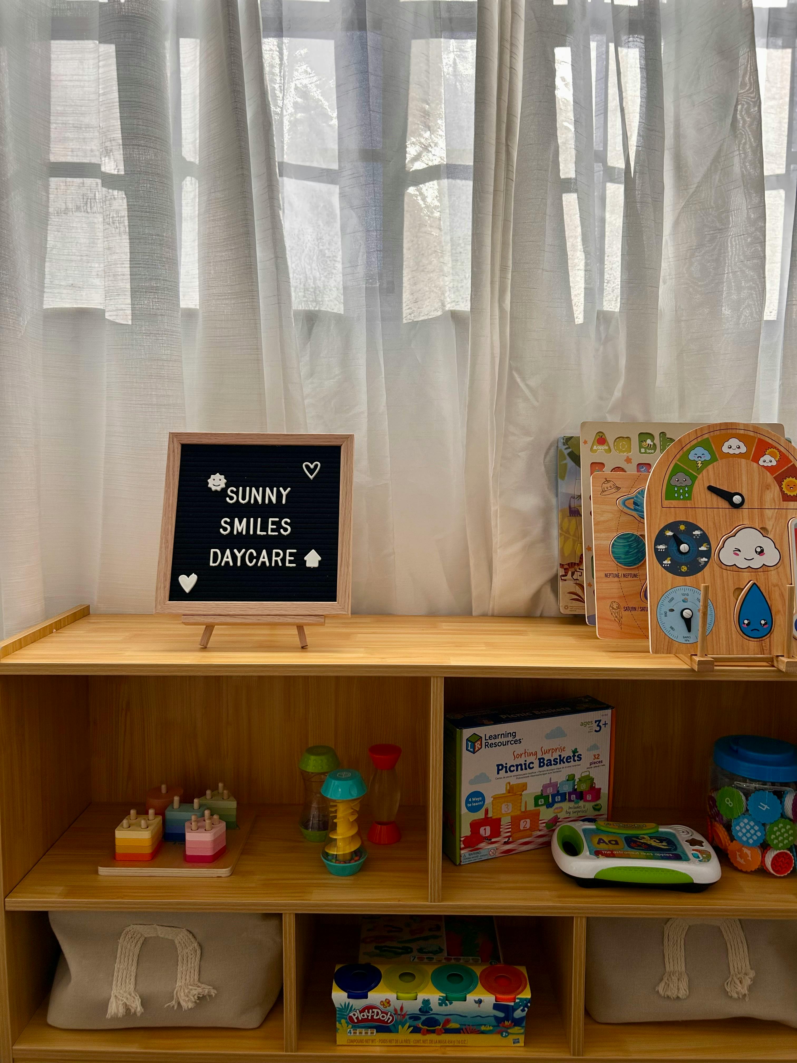 A sign that says "Sunny Smiles Daycare" on a shelf with toys