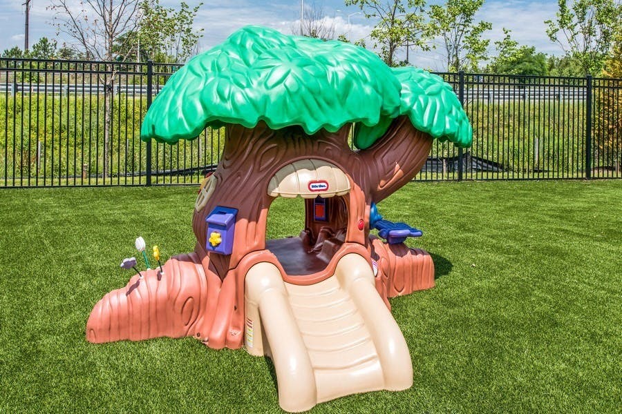 Plastic treehouse play structure with a slide on green grass