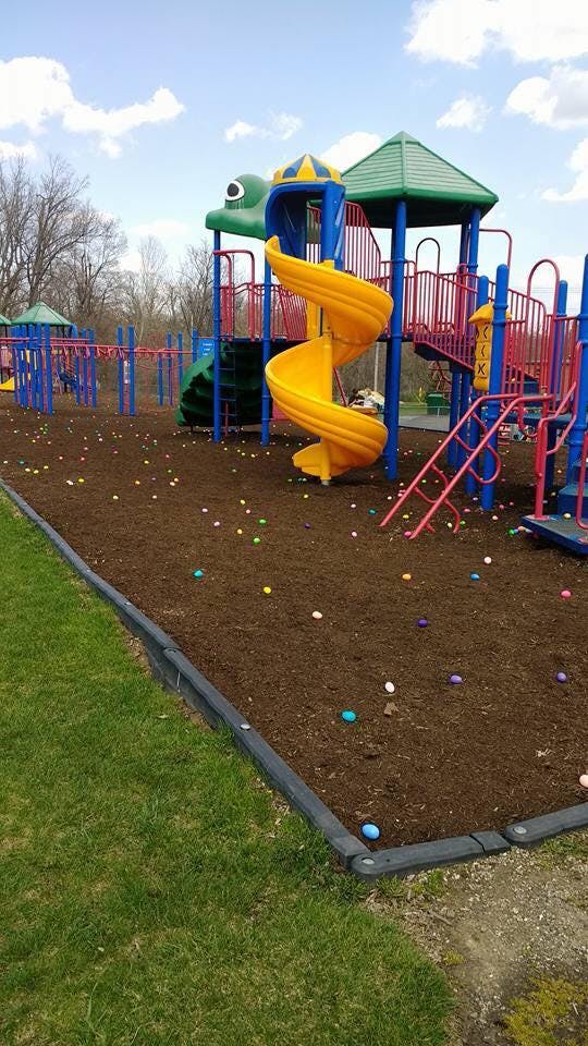 Playground with a yellow spiral slide and colorful plastic eggs on the ground