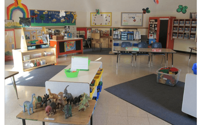 Classroom with tables, chairs, and dinosaur toys on a display