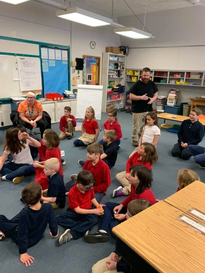 Adults and children sitting on the floor in a classroom