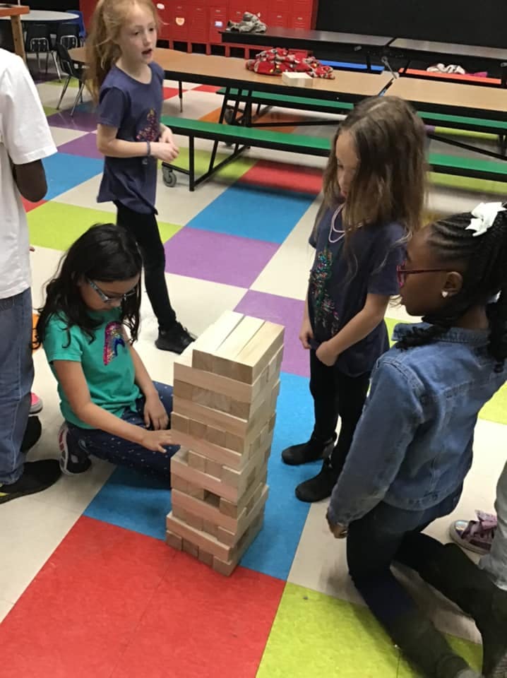 Child playing Jenga with other children watching