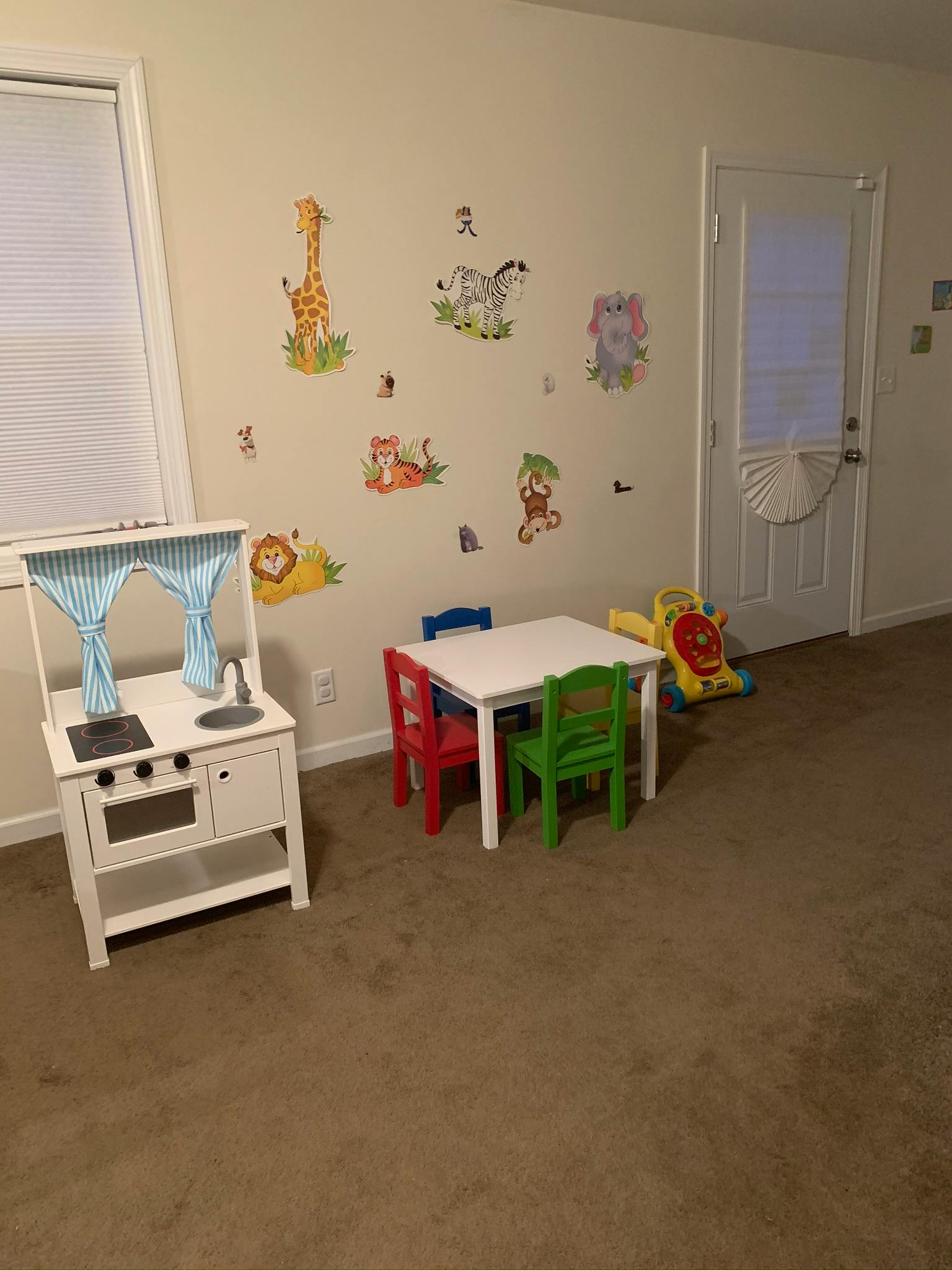 Play kitchen and small table with chairs in a room with animal wall decals