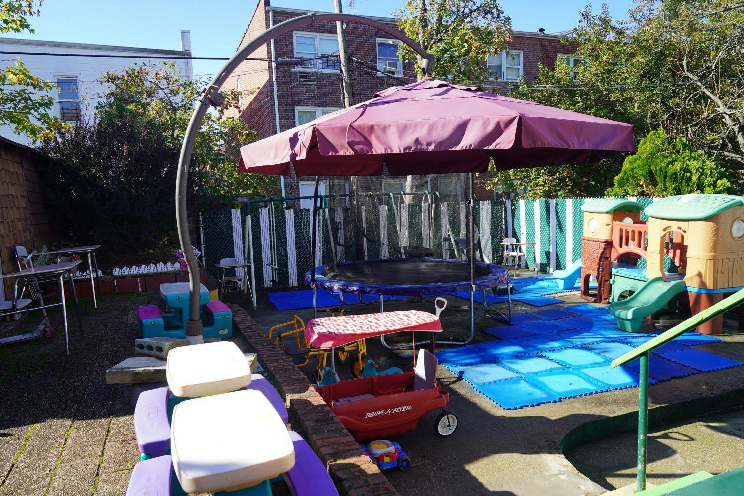 Backyard with a trampoline, playhouse, and blue mats