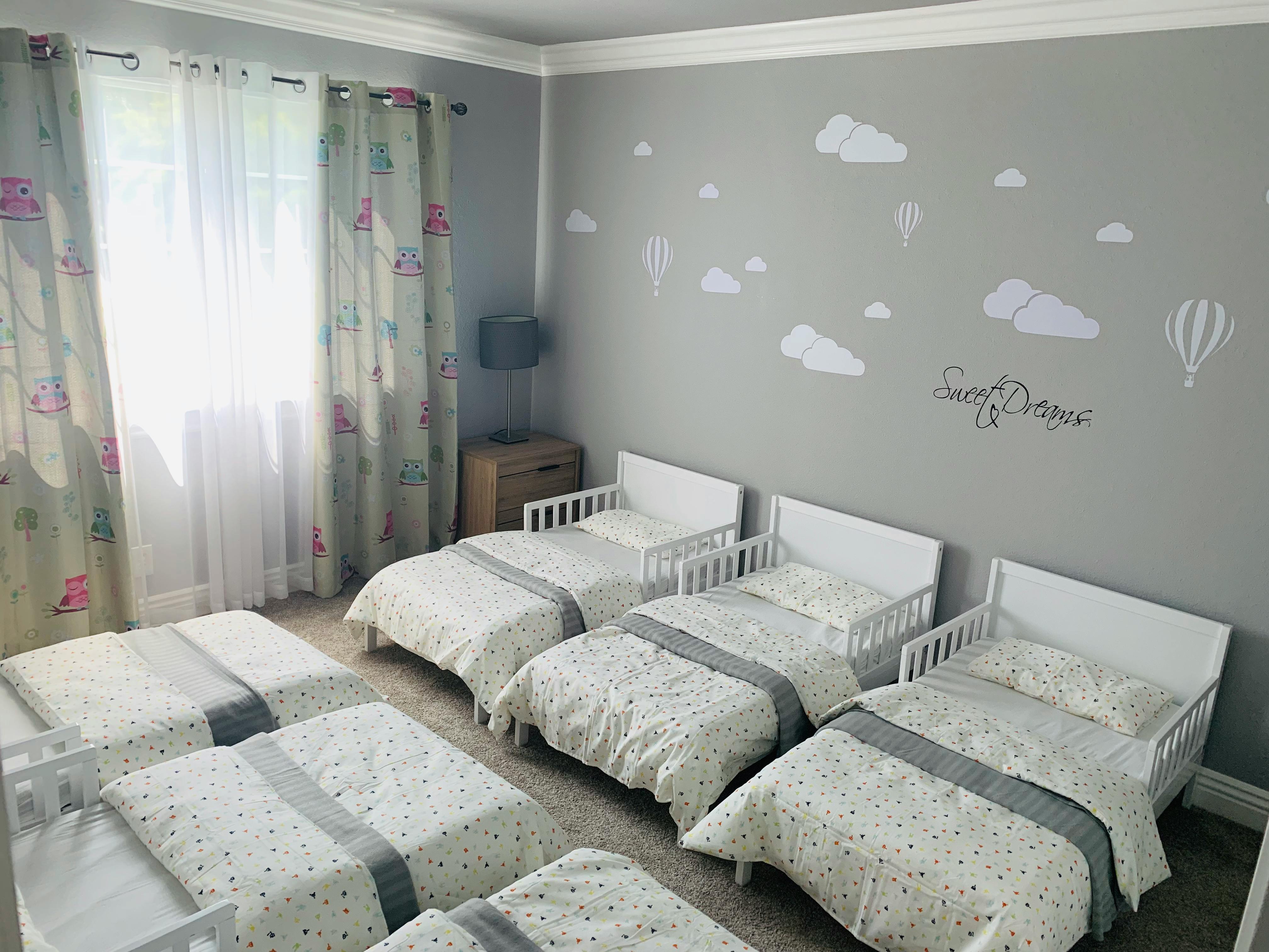 Room with multiple small beds with white bedding and gray accents