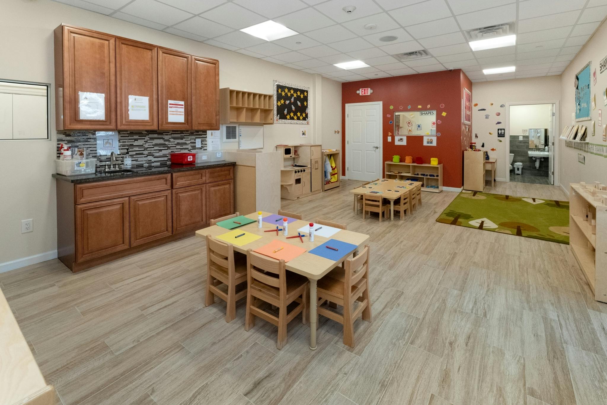 Classroom with small tables and chairs, and a counter with cabinets