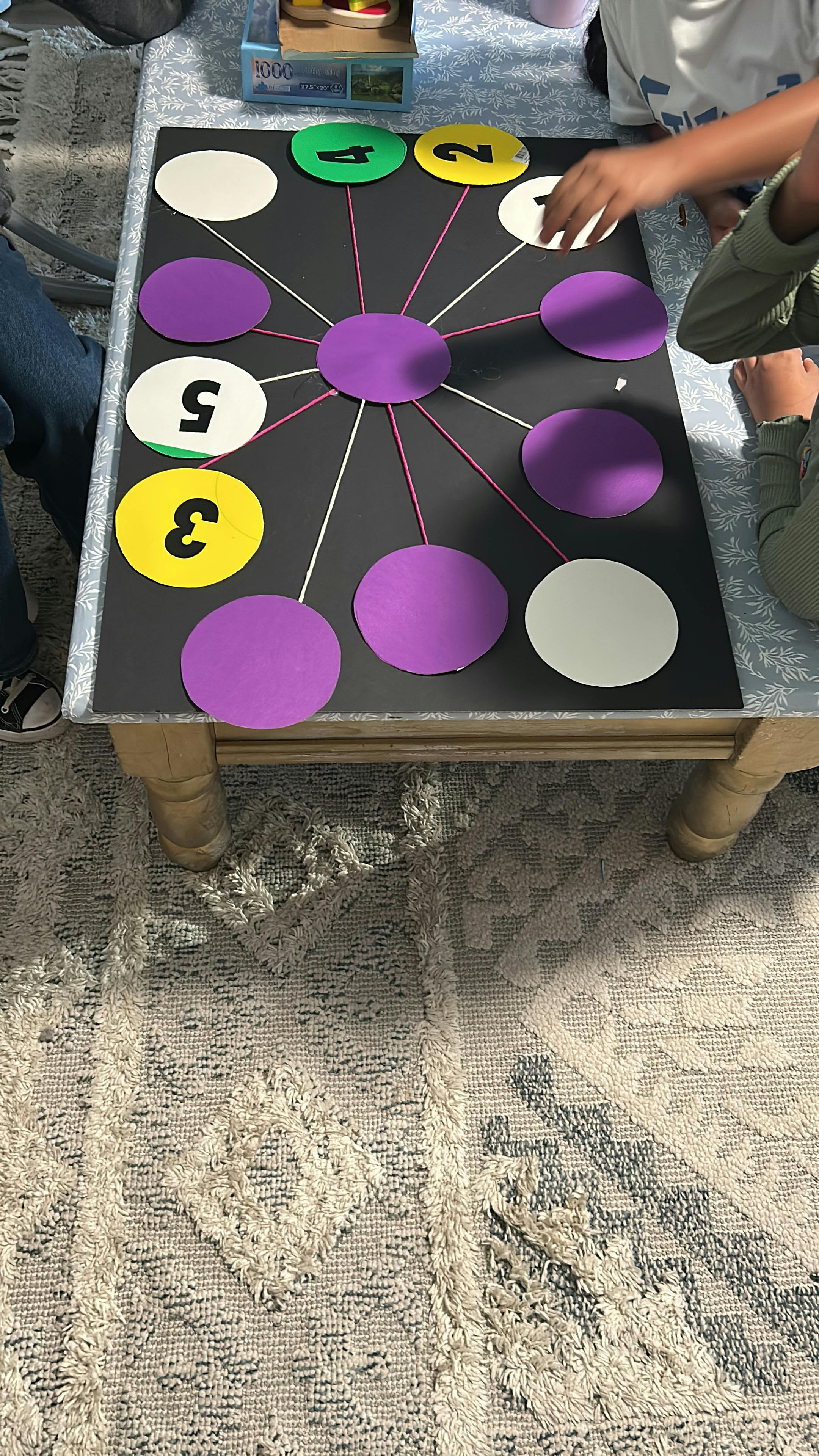 People playing a game with numbered and colored circles on a black board