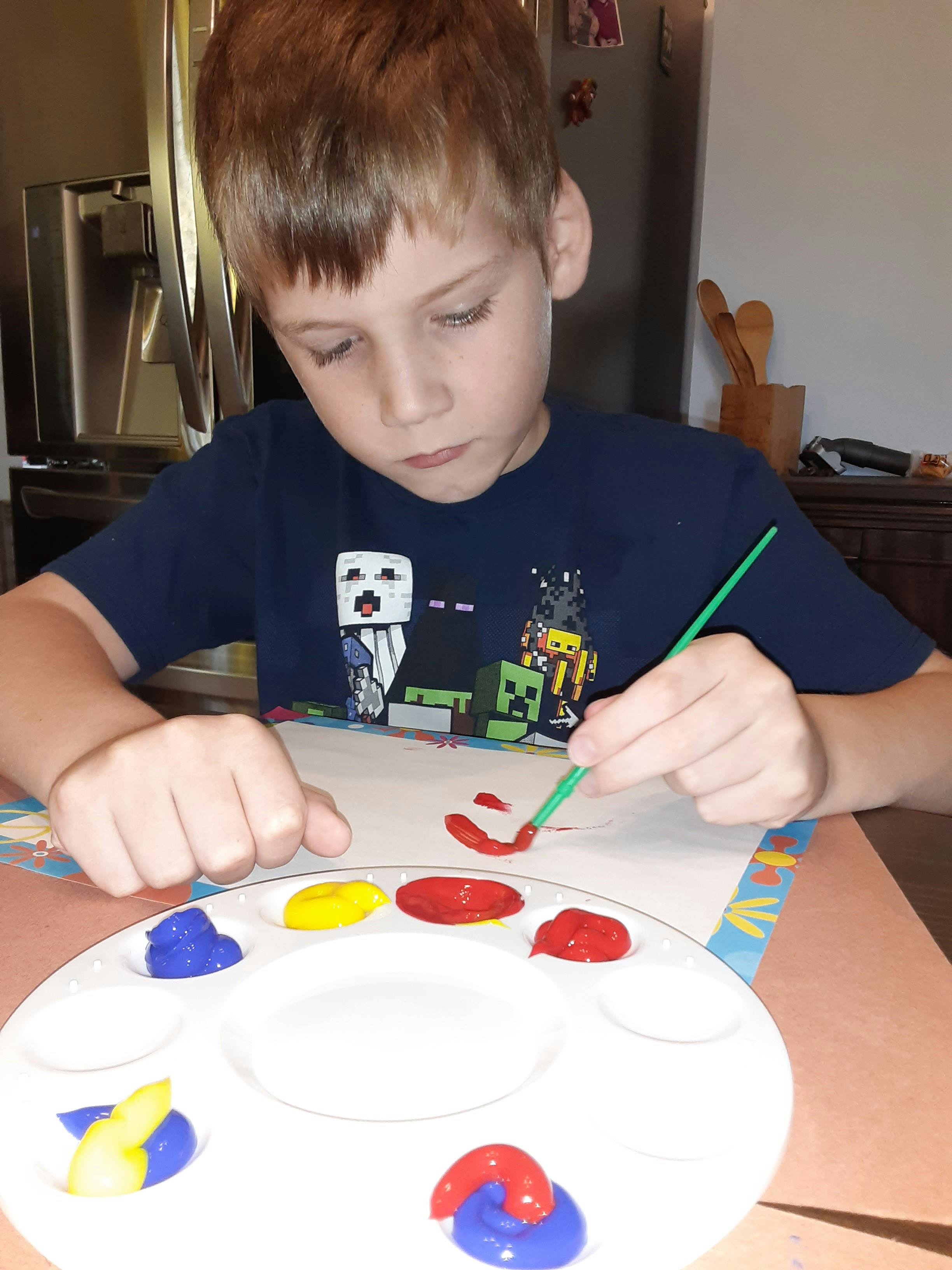 Child painting with a brush and paint palette