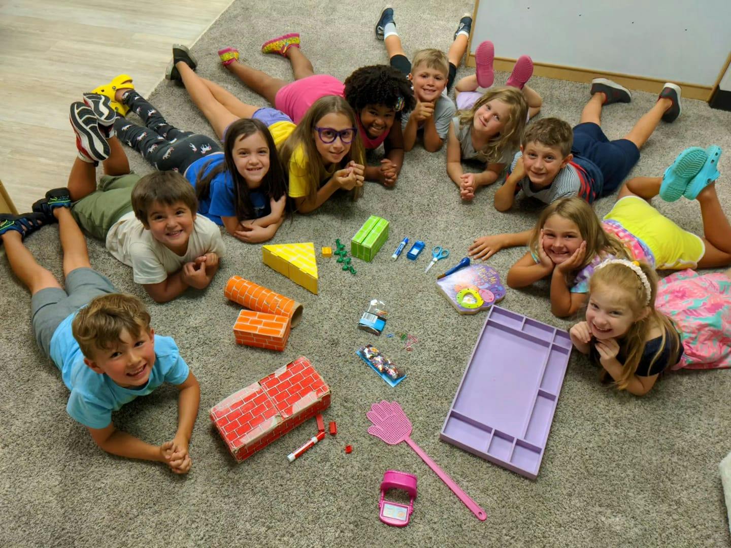Group of children lying on the floor in a circle with toys