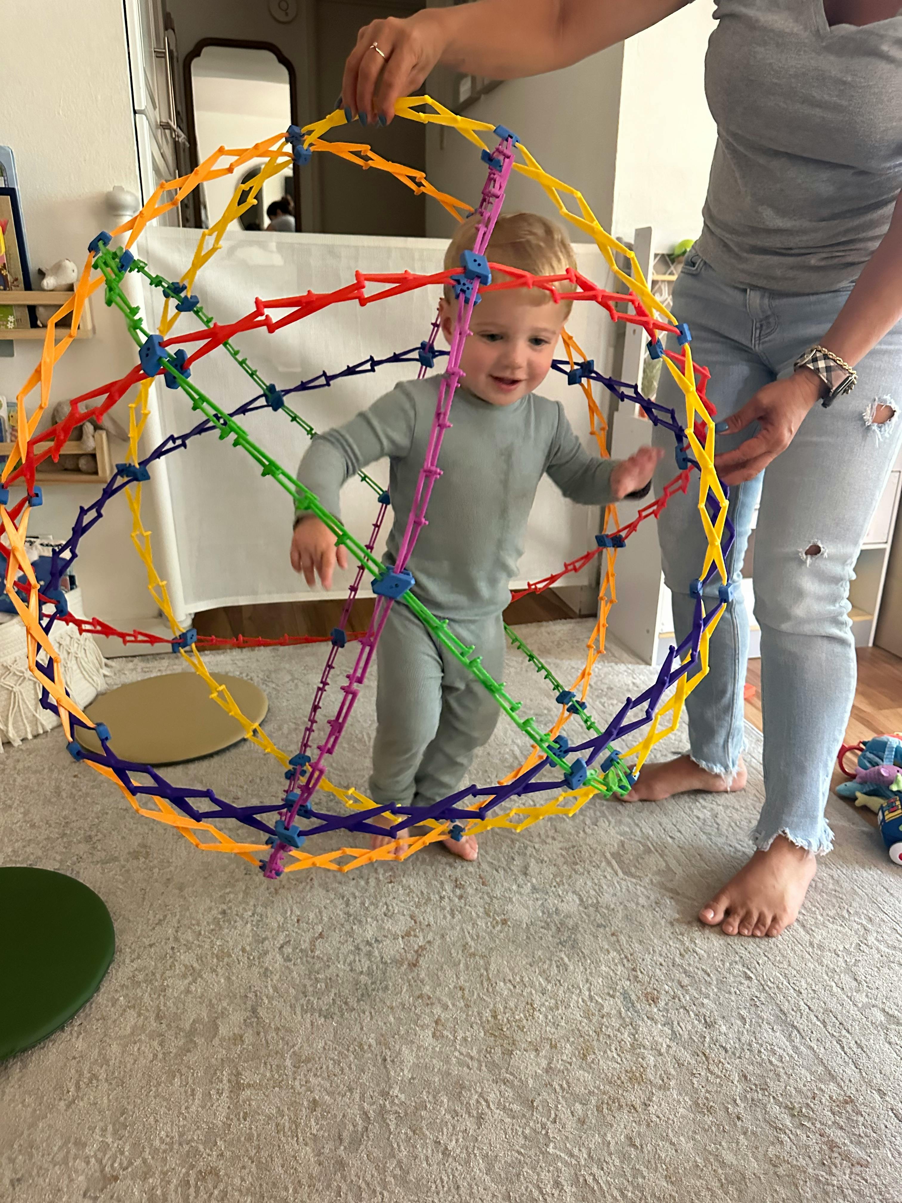 Person holding a colorful geometric toy around a child