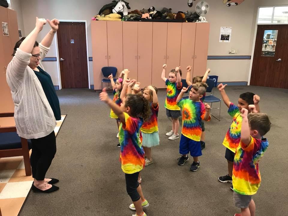 Adult and children in tie-dye shirts raising their arms