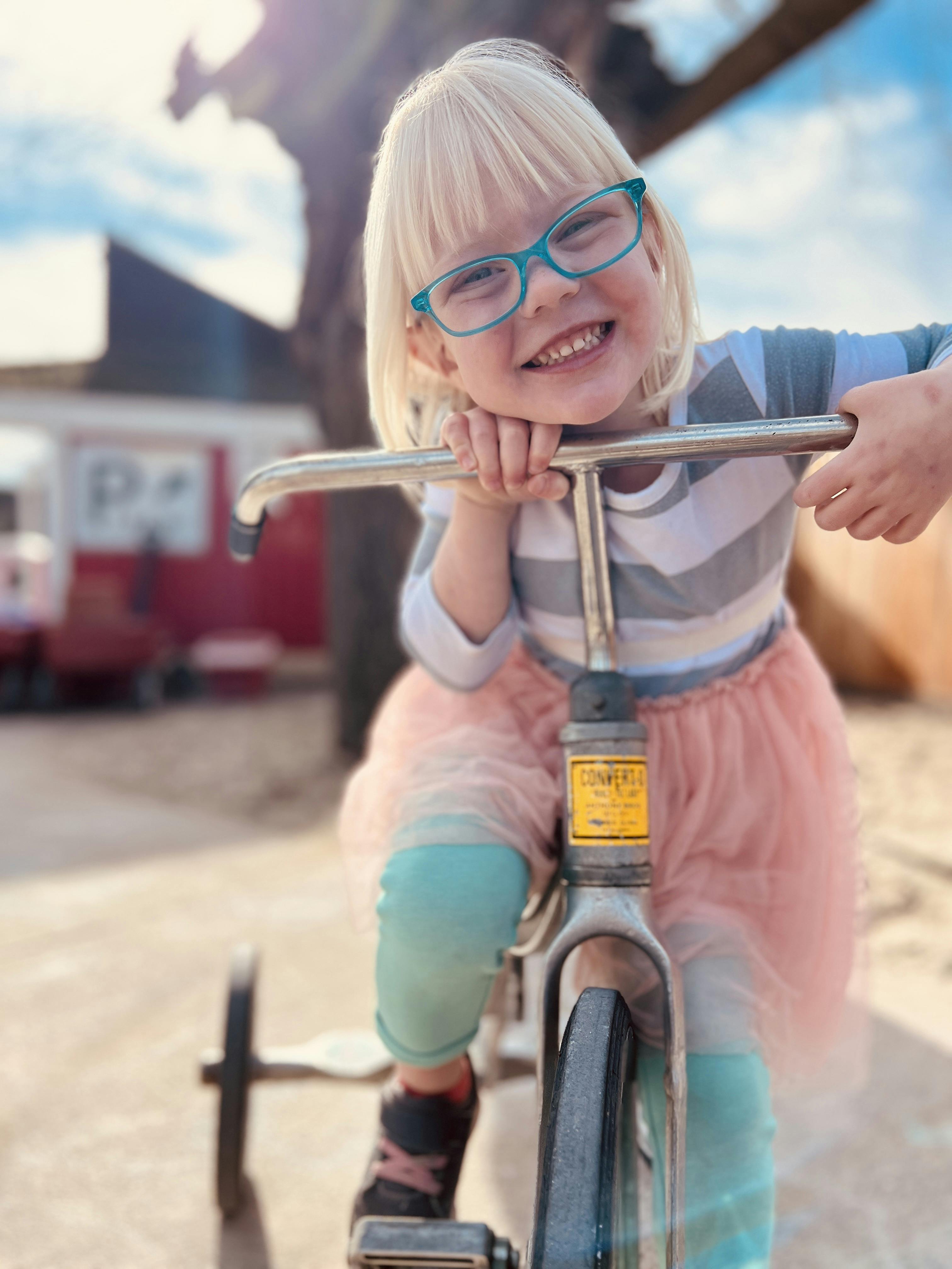 Child with glasses on a tricycle