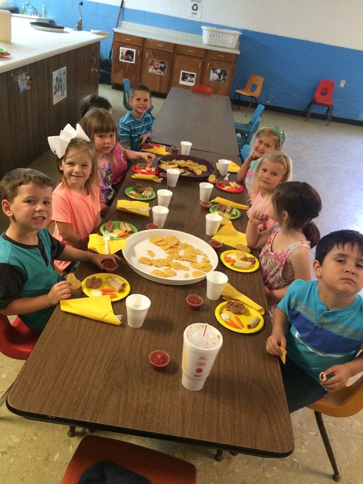 Children sitting at a long table with plates of food