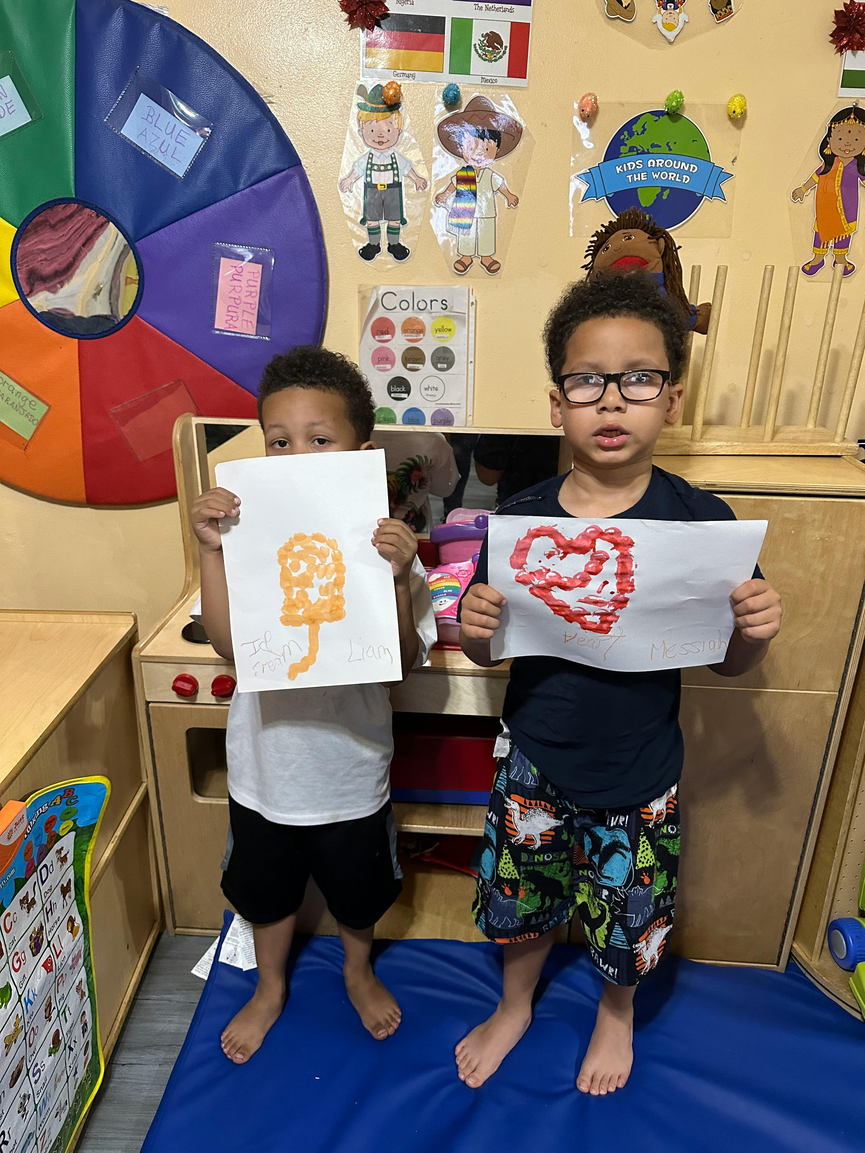 Two children holding up artwork in a classroom