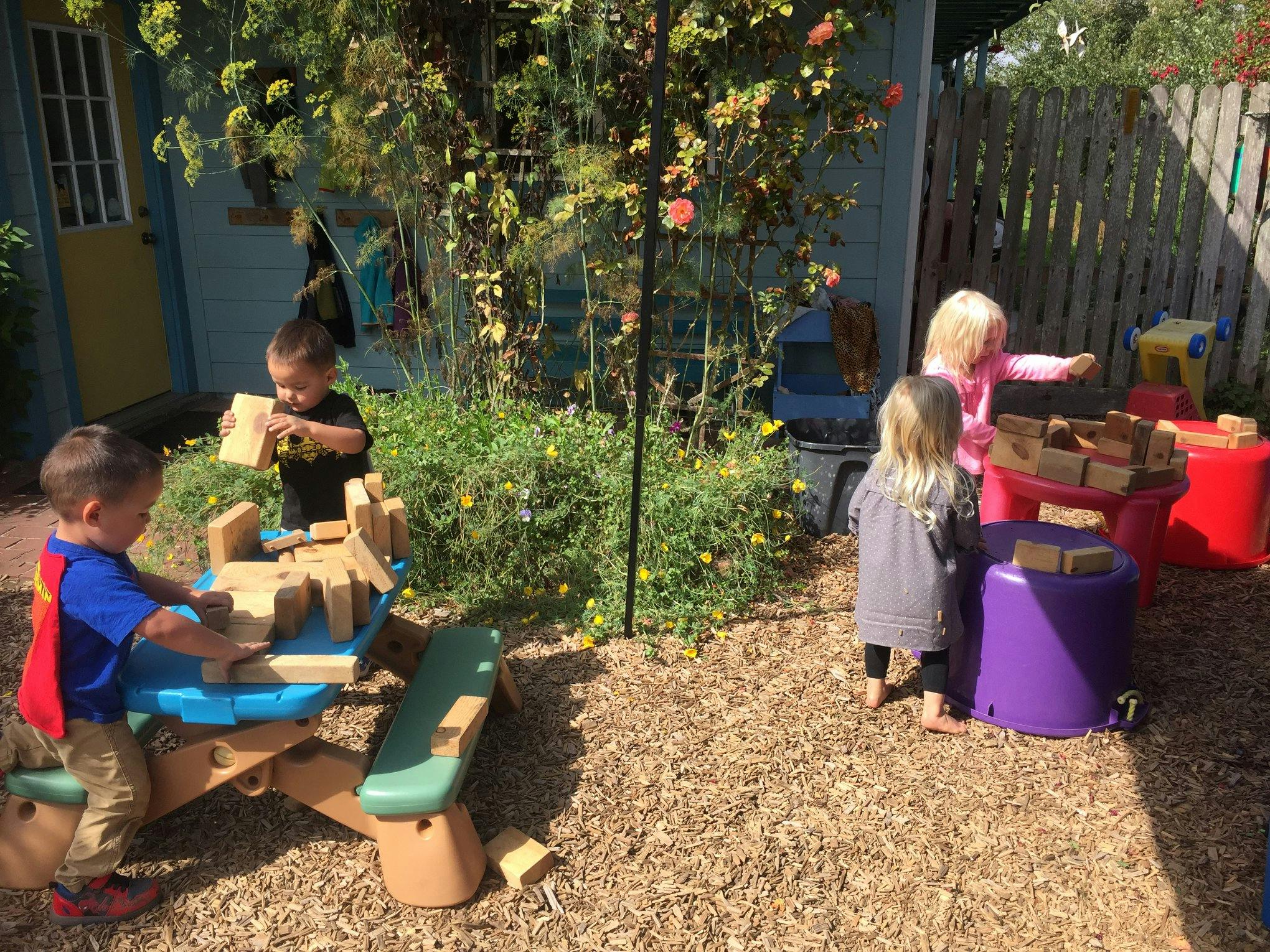 Children playing with wooden blocks outdoors