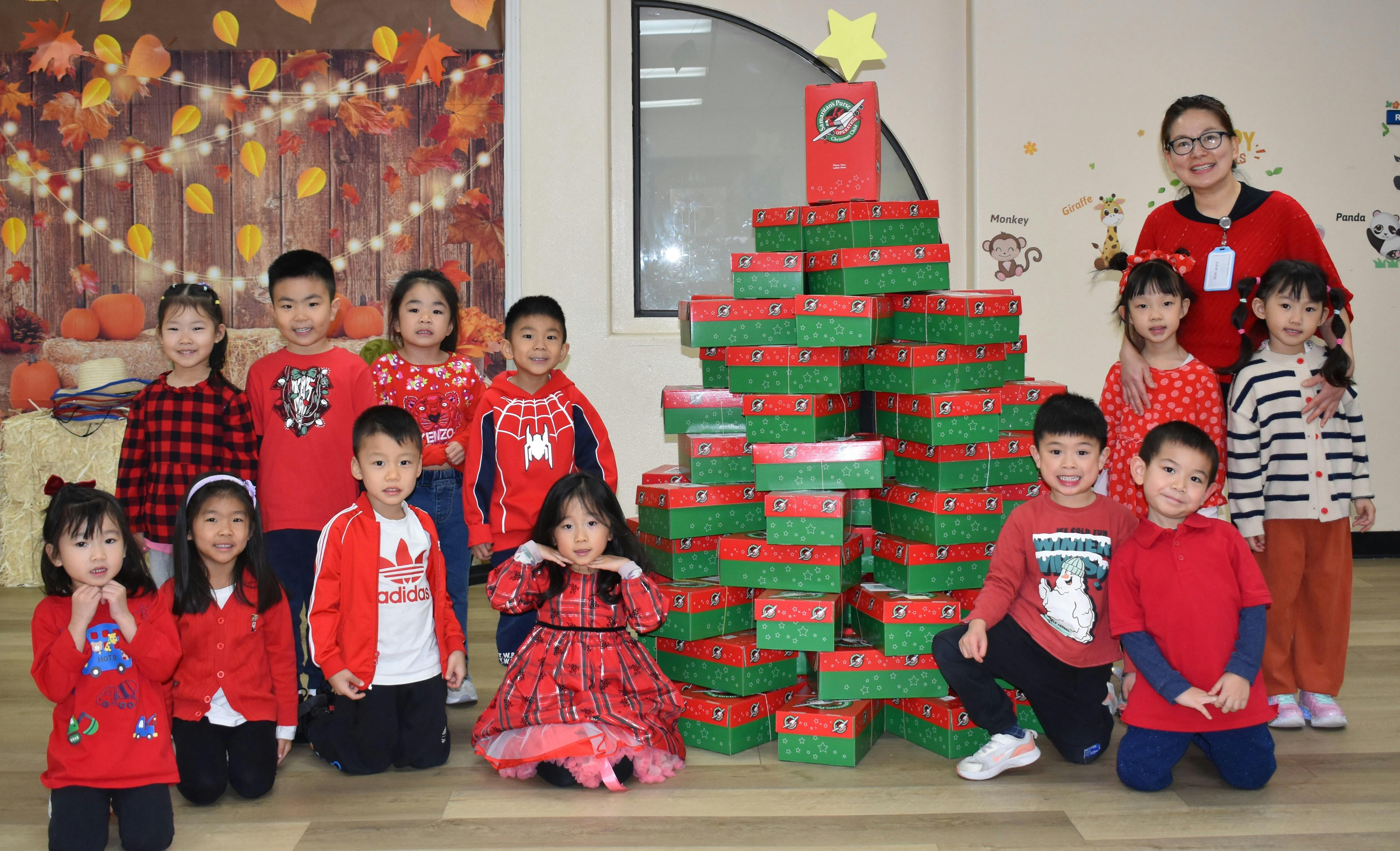 Group of children and an adult posing with a stack of gift boxes