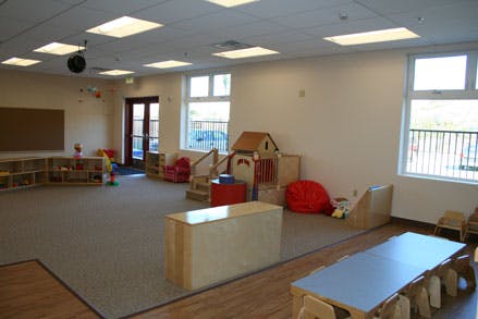 Empty classroom with play structures, tables, and chairs
