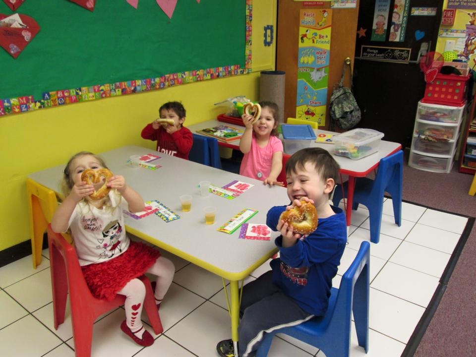 Children eating pretzels at a table in a classroom