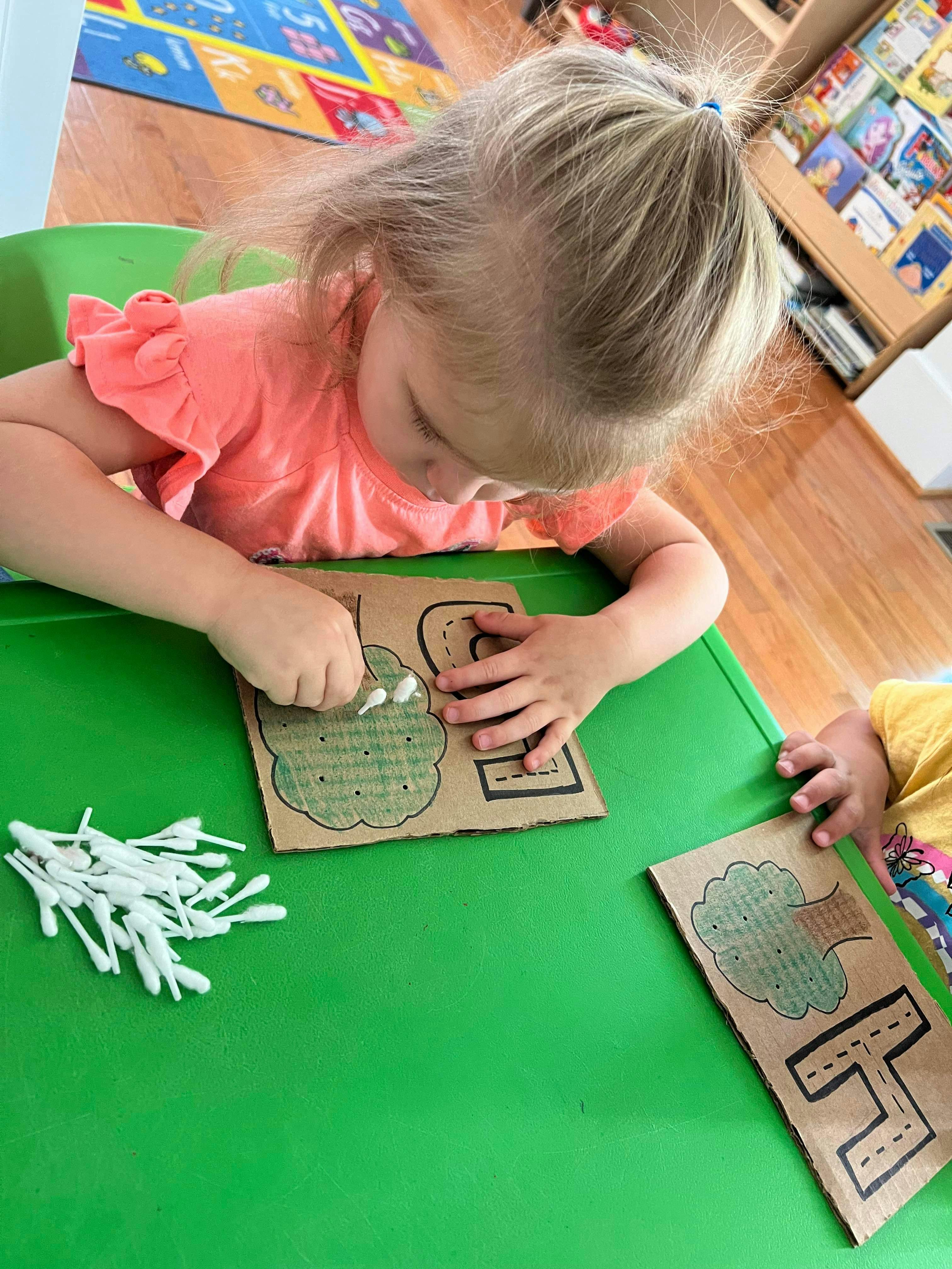 Child doing an art activity with cotton swabs and cardboard cutouts