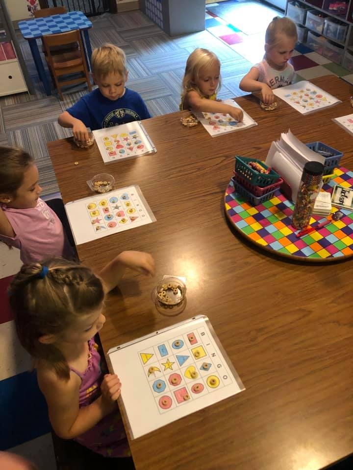 Children sitting at a table doing an activity with shapes