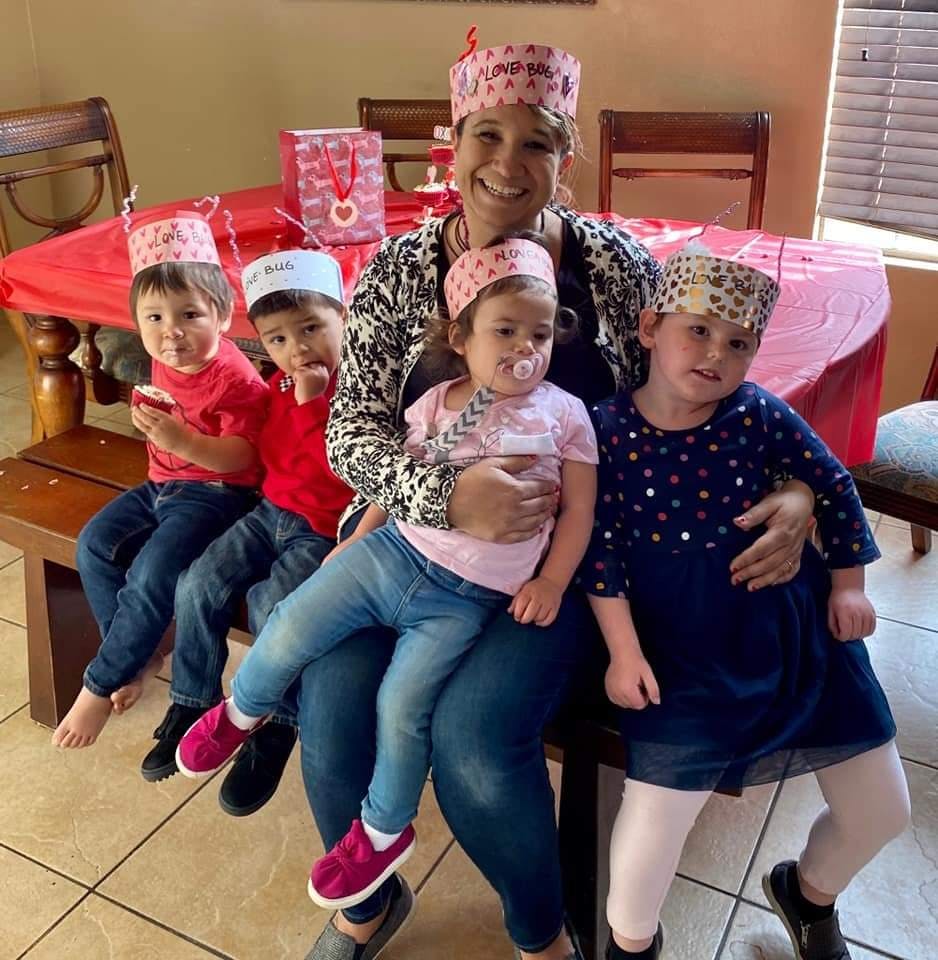 Person sitting with four children, all wearing paper crowns