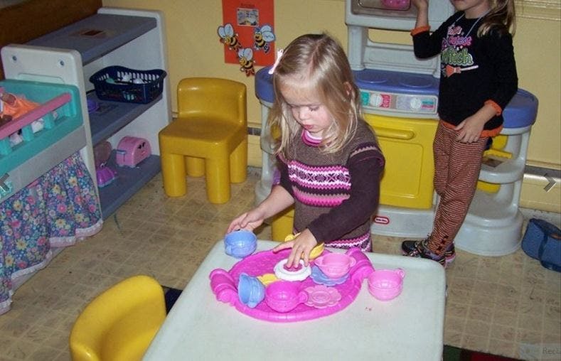 Child playing with a toy tea set at a table