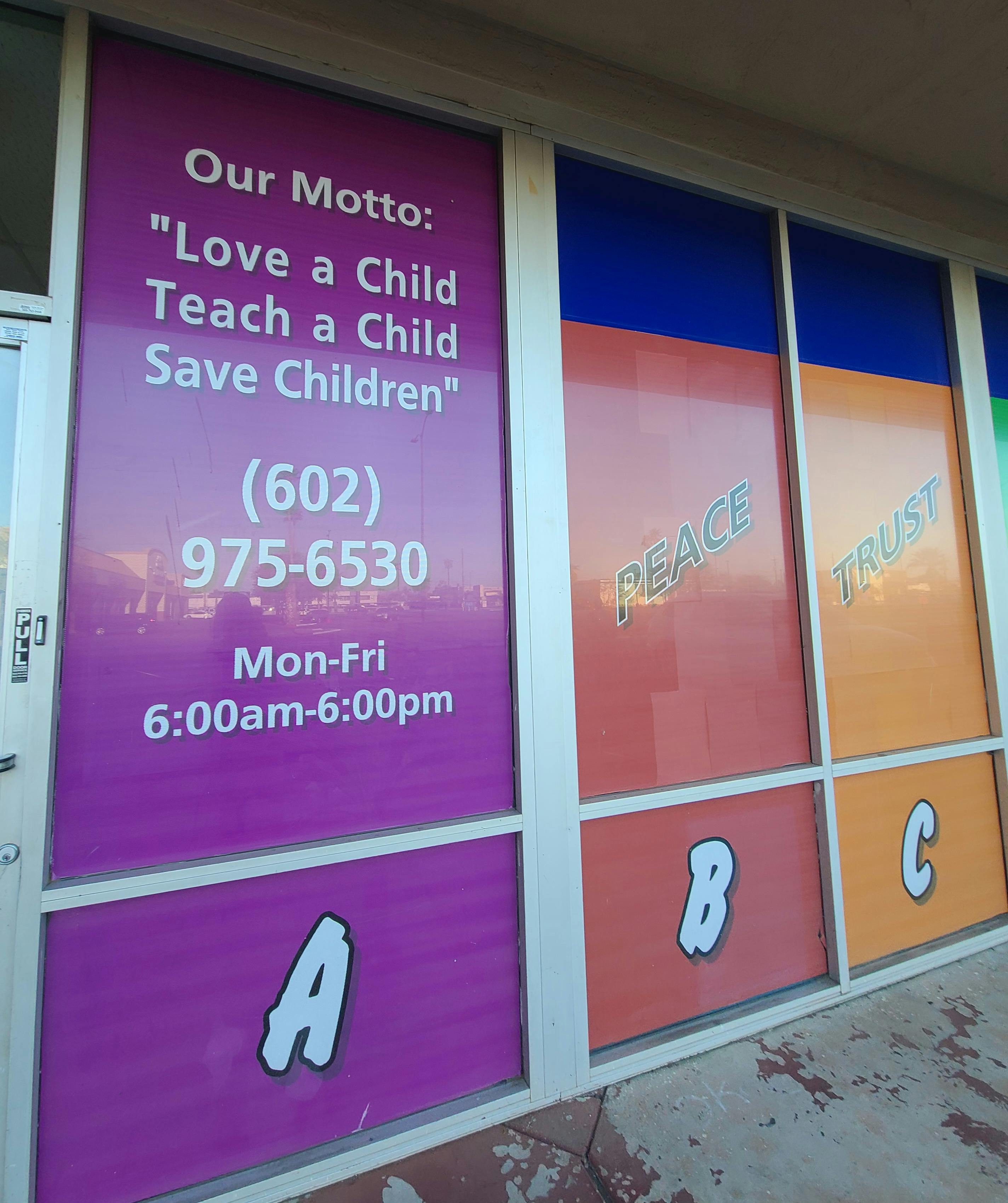 Storefront windows with text "Love a Child Teach a Child Save Children" and "Peace Trust"