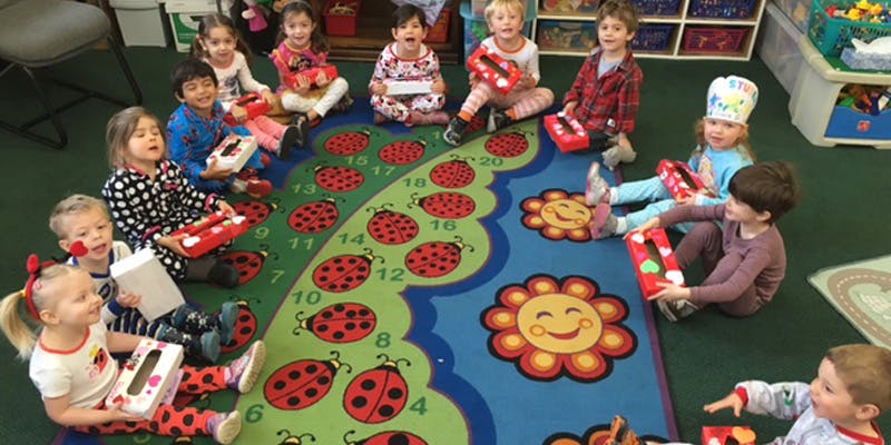 Children sitting in a circle on a ladybug-themed rug