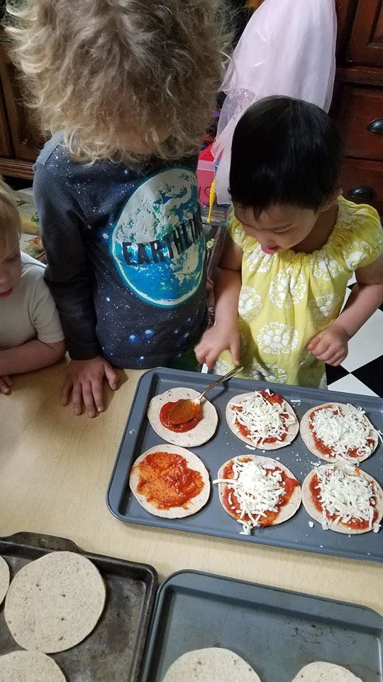 Children making mini pizzas on baking sheets