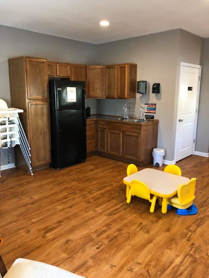 Kitchenette with wooden cabinets, black refrigerator, and small yellow table with chairs