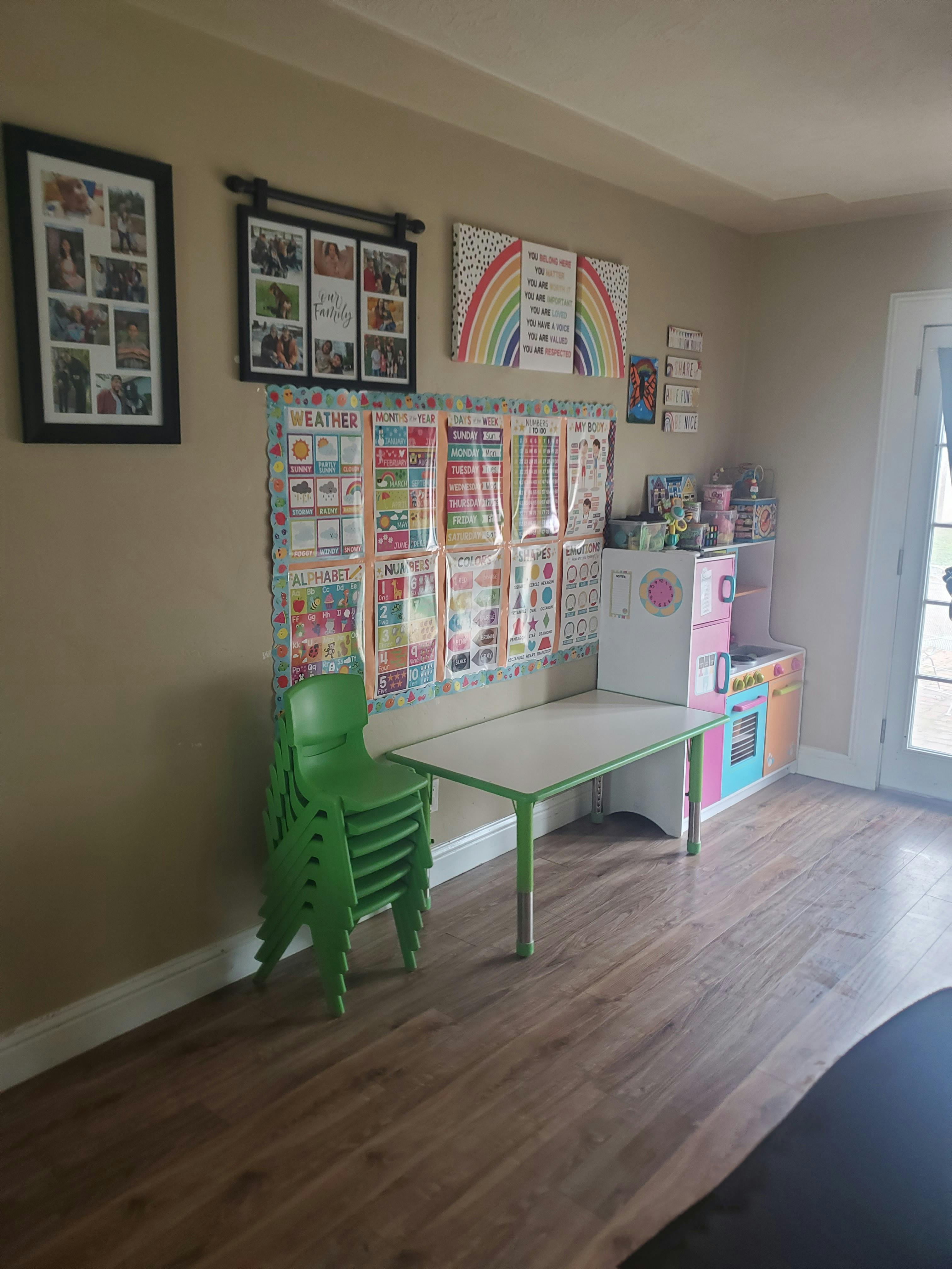Classroom with a small table, stacked chairs, and educational posters on the wall