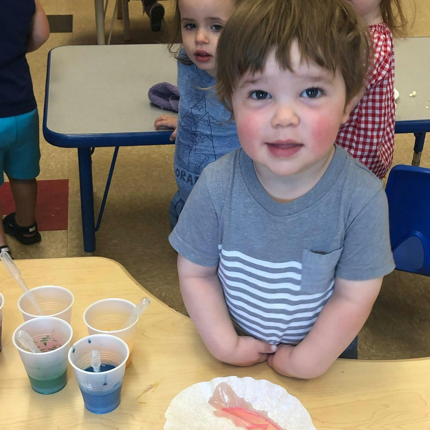 Child in gray shirt with white stripes looking at camera