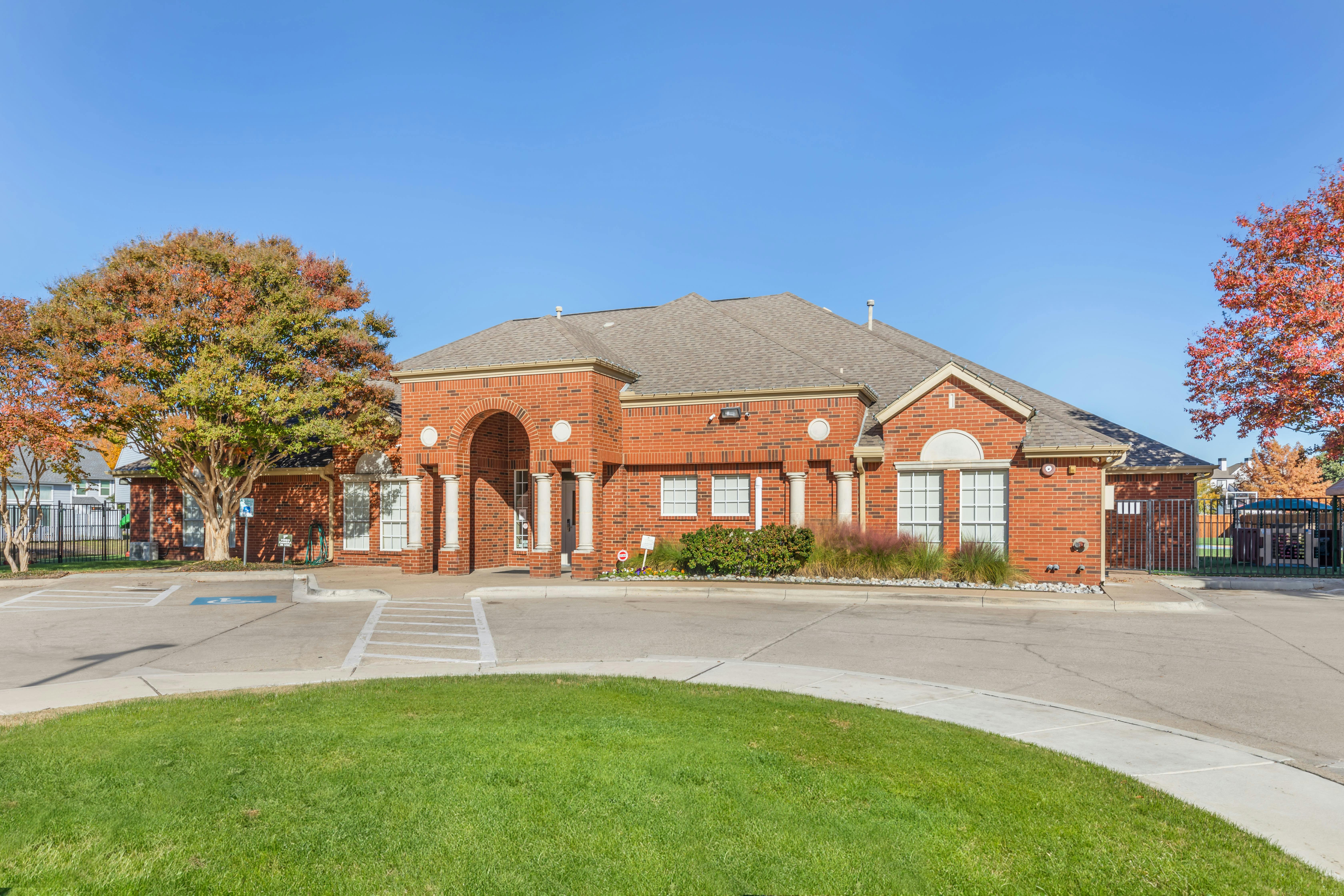 Red brick building with an arched entrance and large columns, surrounded by trees