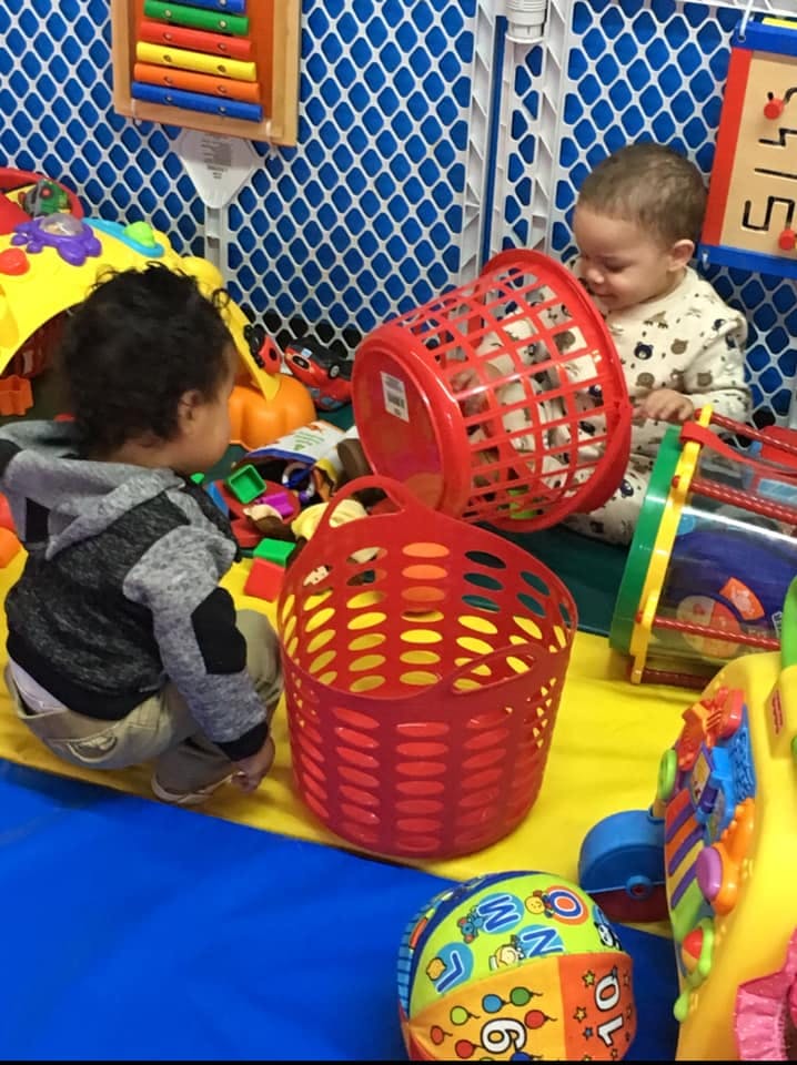 Two children playing with toys and red baskets in a play area