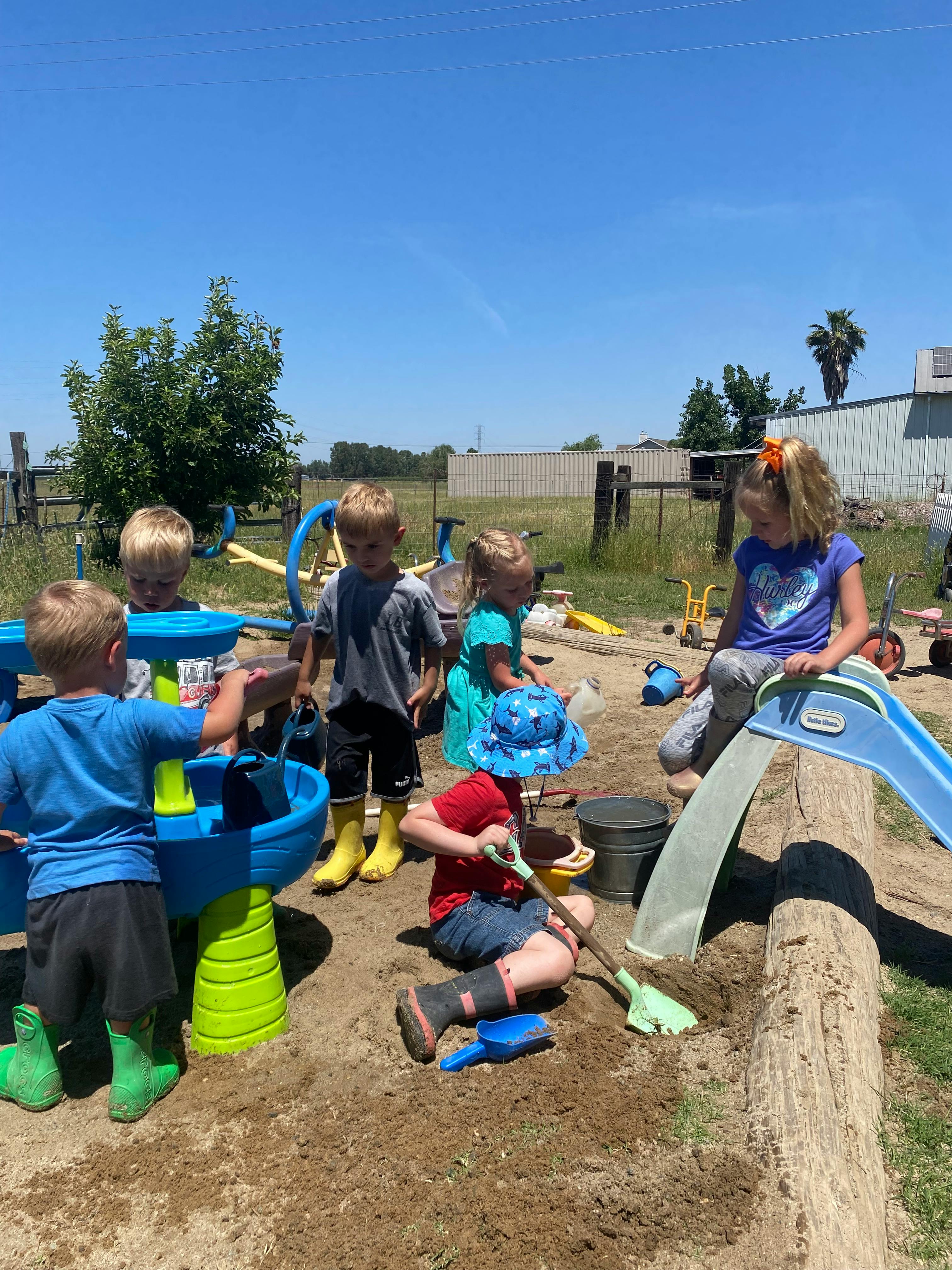 Children playing in a sandbox with water toys and toys