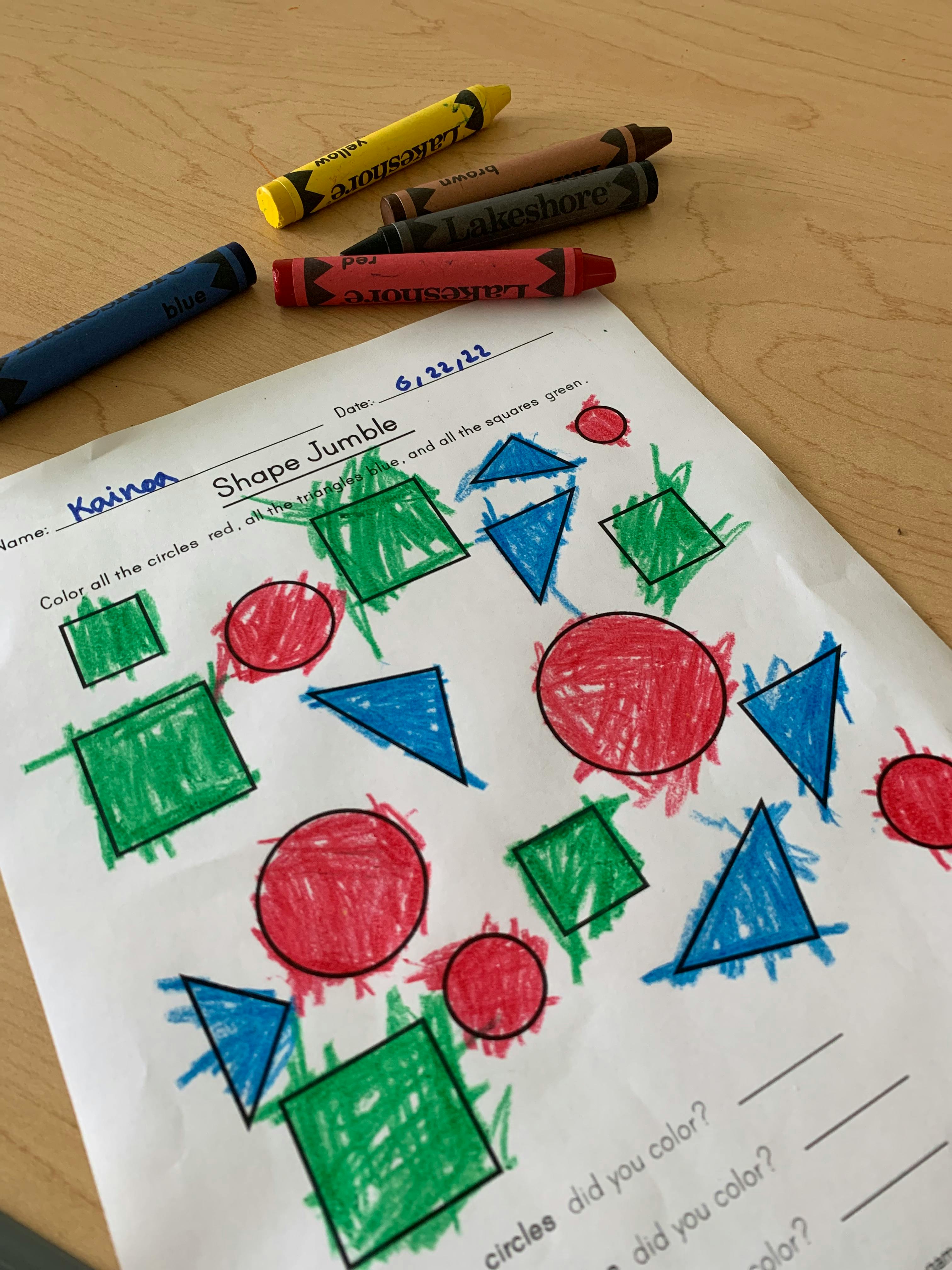 Crayons next to a worksheet with colored shapes
