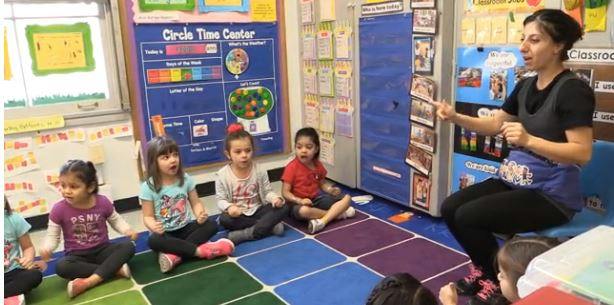 Person speaking to children sitting on a classroom floor
