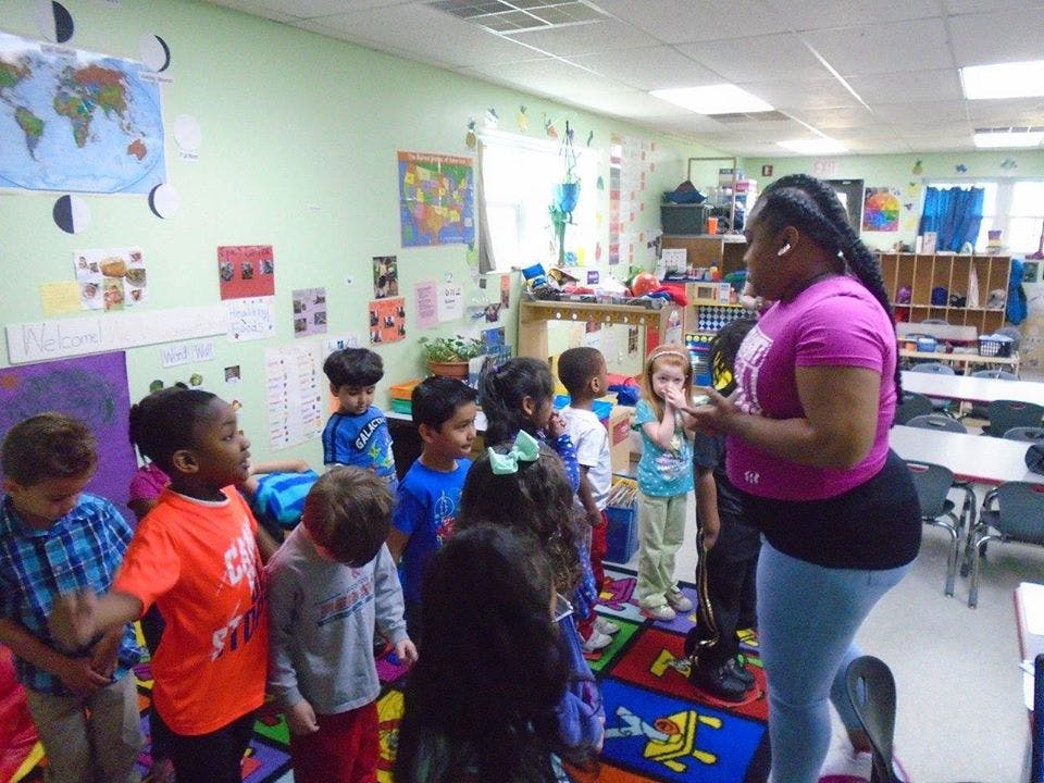 Person speaking to a group of children in a classroom