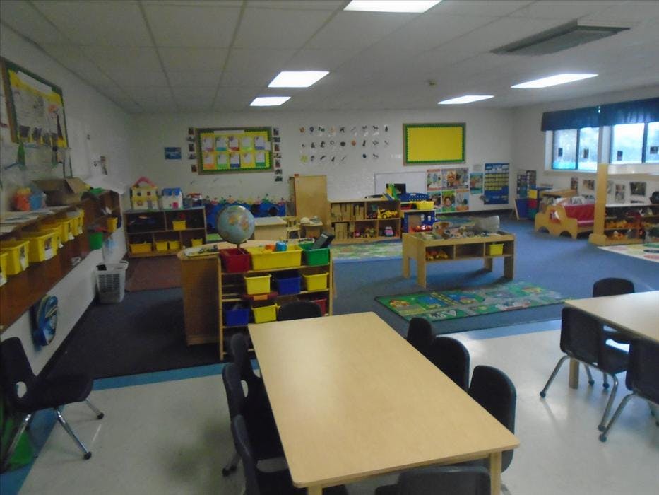 Classroom with tables, chairs, shelving units, and toys