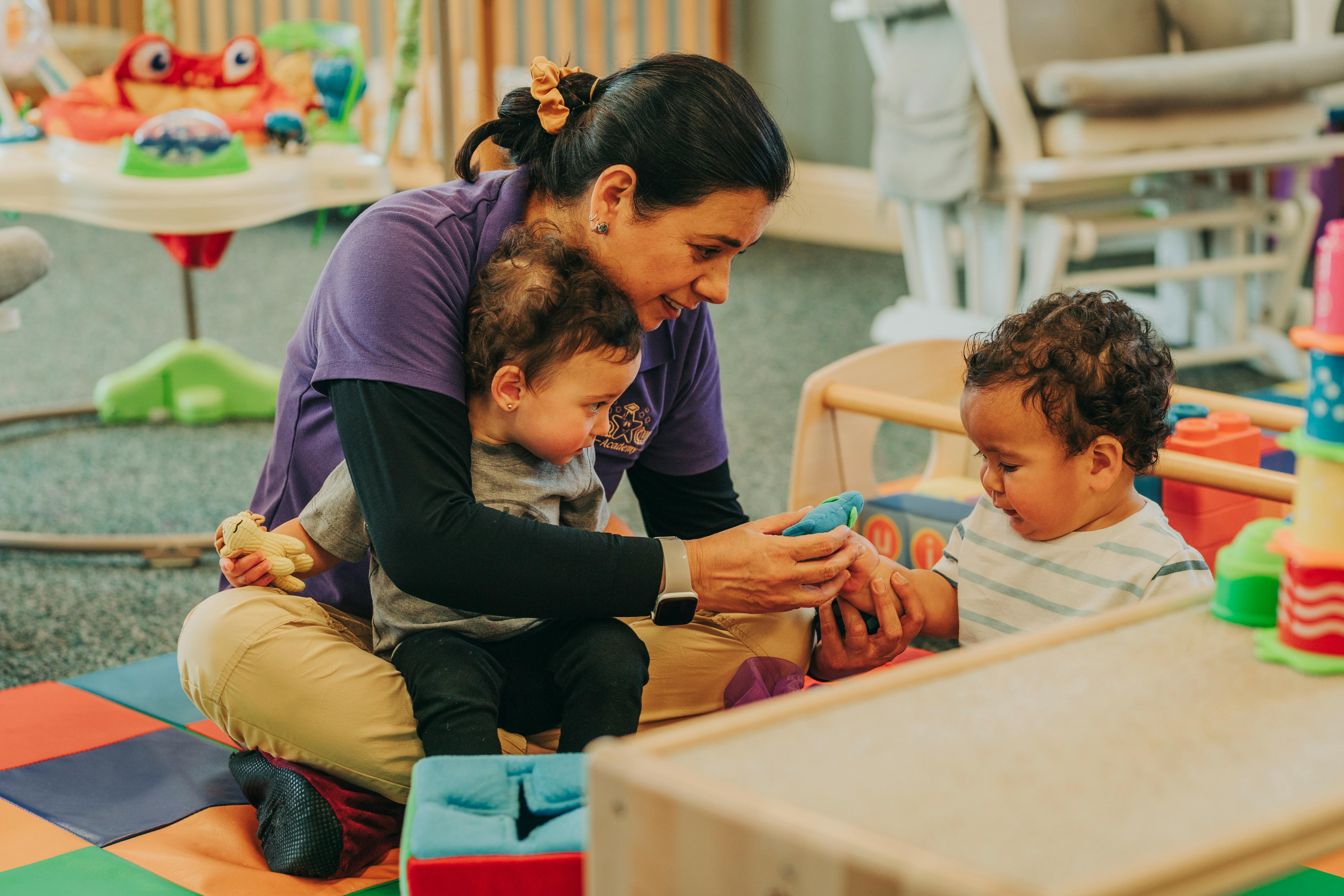 Person sitting on floor with two children, holding an object between them