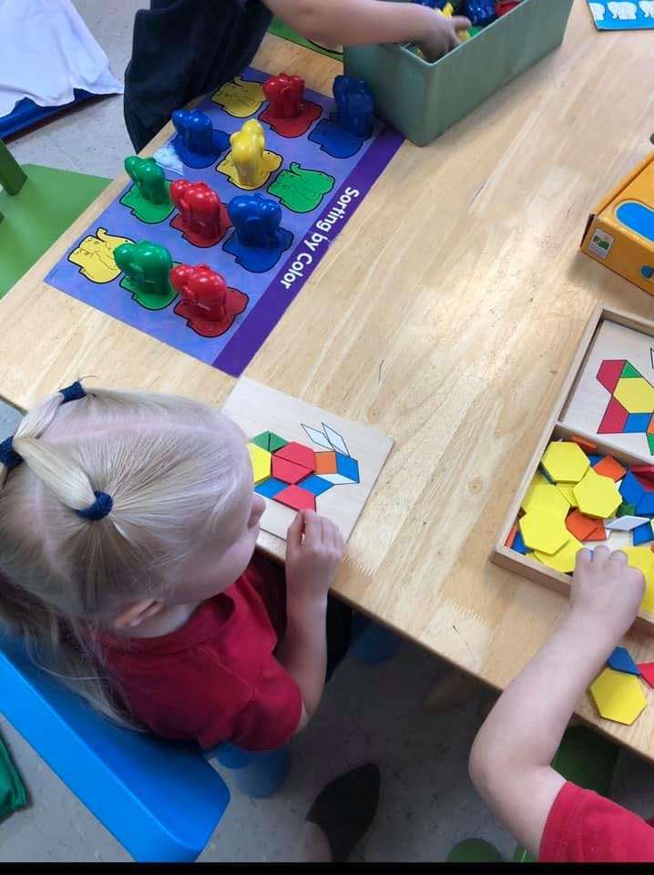 Children playing with colorful sorting and pattern-making toys at a table