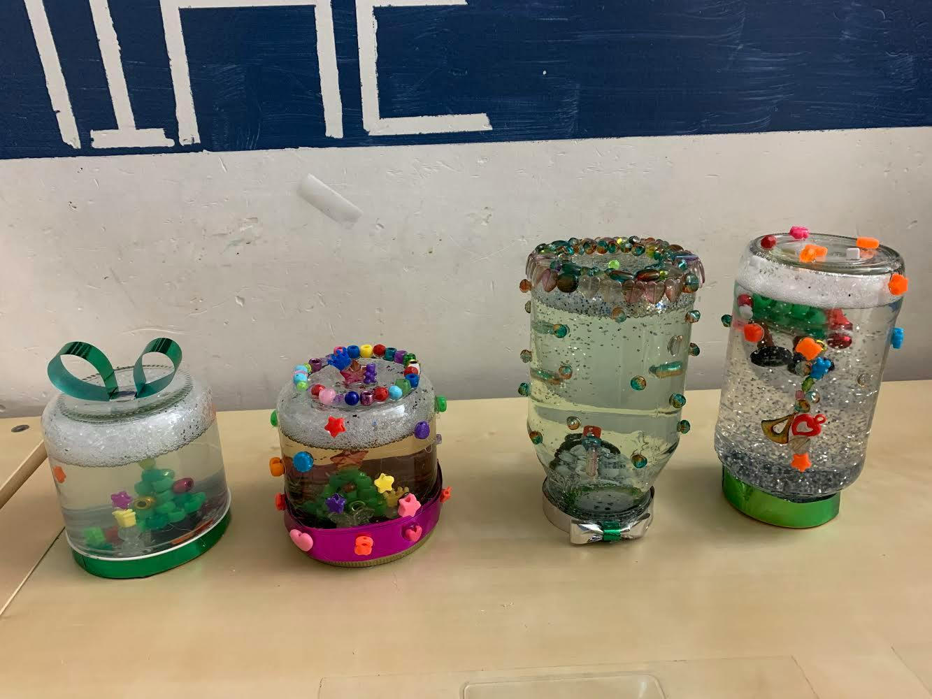 Four decorated jars with glitter and small objects inside