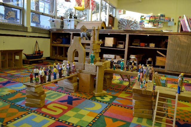 Toy figures on wooden blocks and structures in a classroom