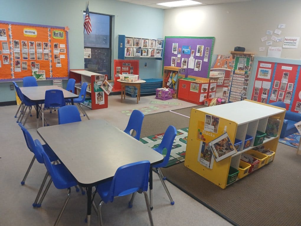 Classroom with child-sized tables and chairs, bulletin boards, and storage shelves