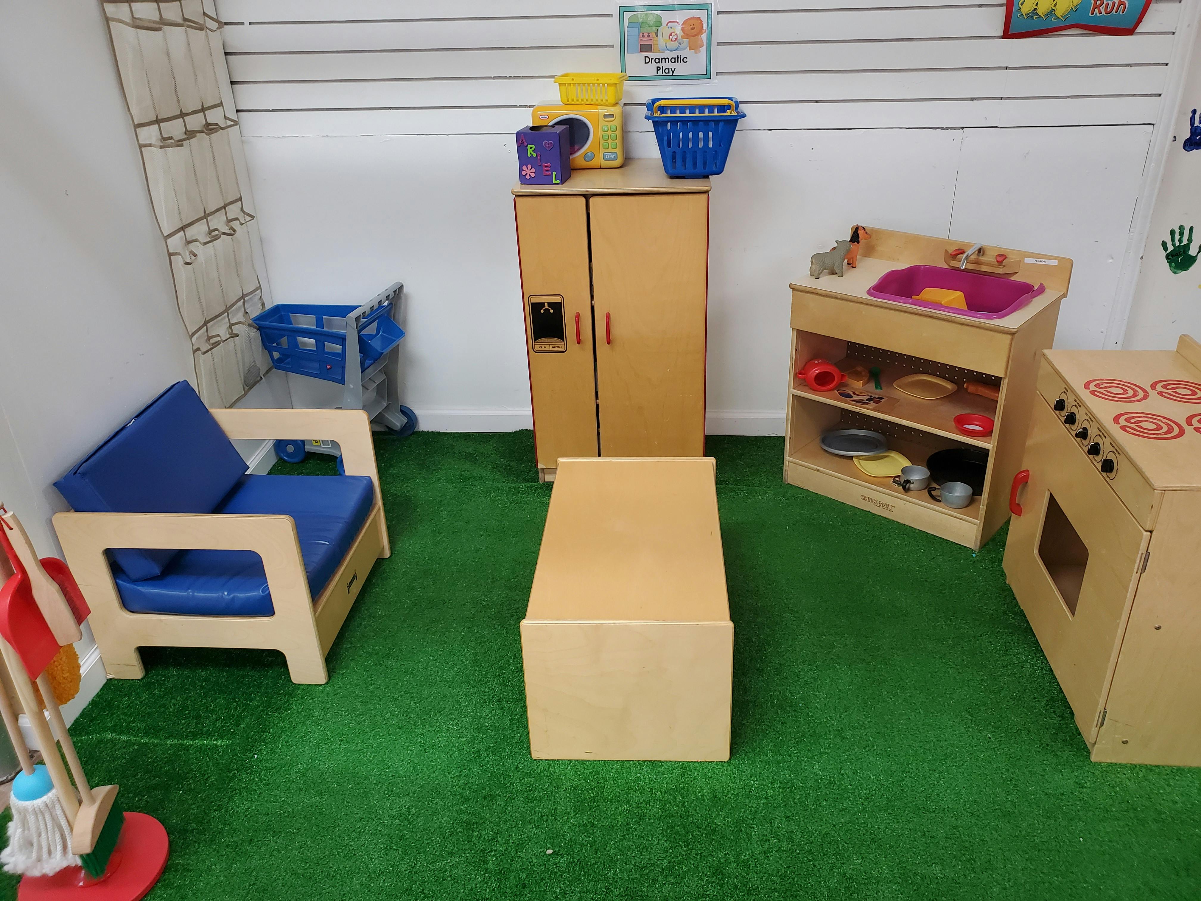 Playroom with child-sized furniture including a chair, table, and play kitchen