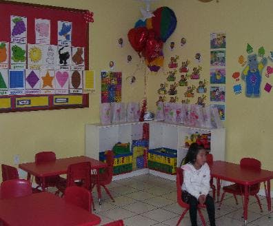 Child sitting at a red table in a classroom