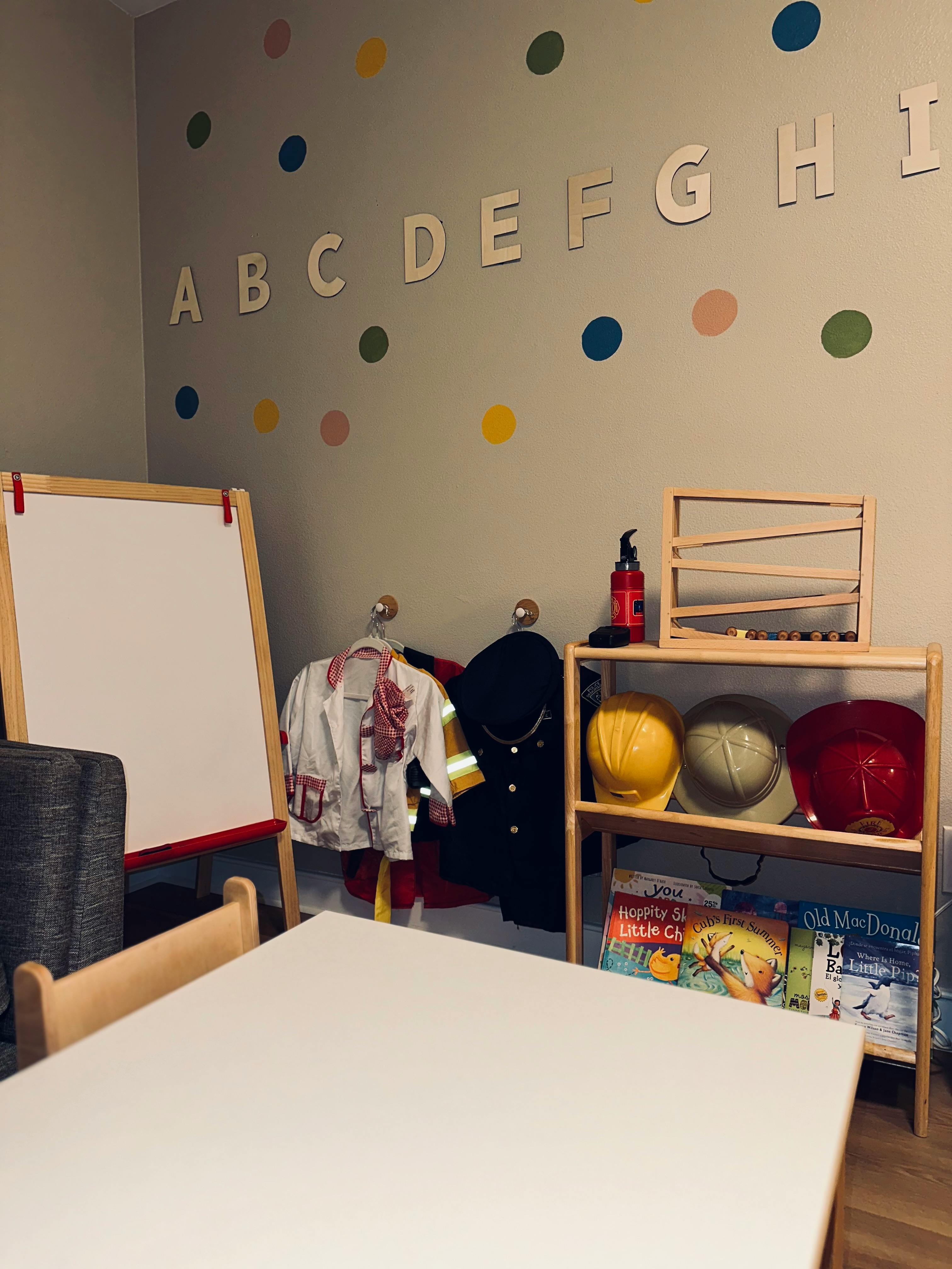 Classroom with whiteboard, dress-up clothes, and shelves with books and helmets